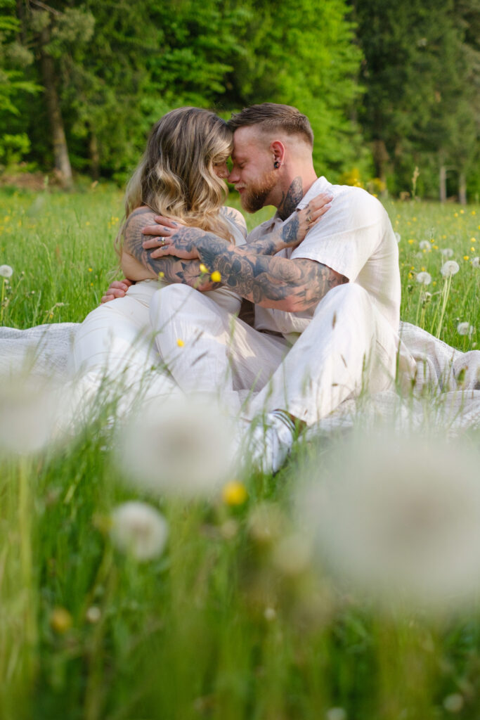 Paar auf einer Wiese mit Pusteblumen im Vordergrund