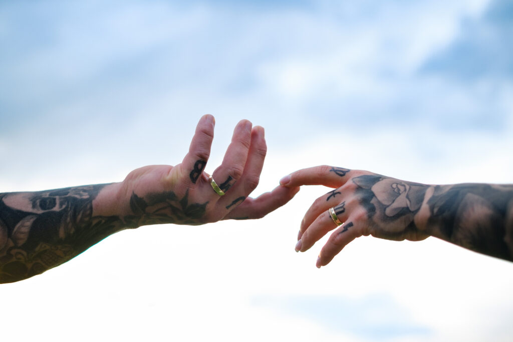 Hände mit Eheringen berühren sich nur an den Fingerspitzen der Zeigefinger, Himmel im Hintergrund